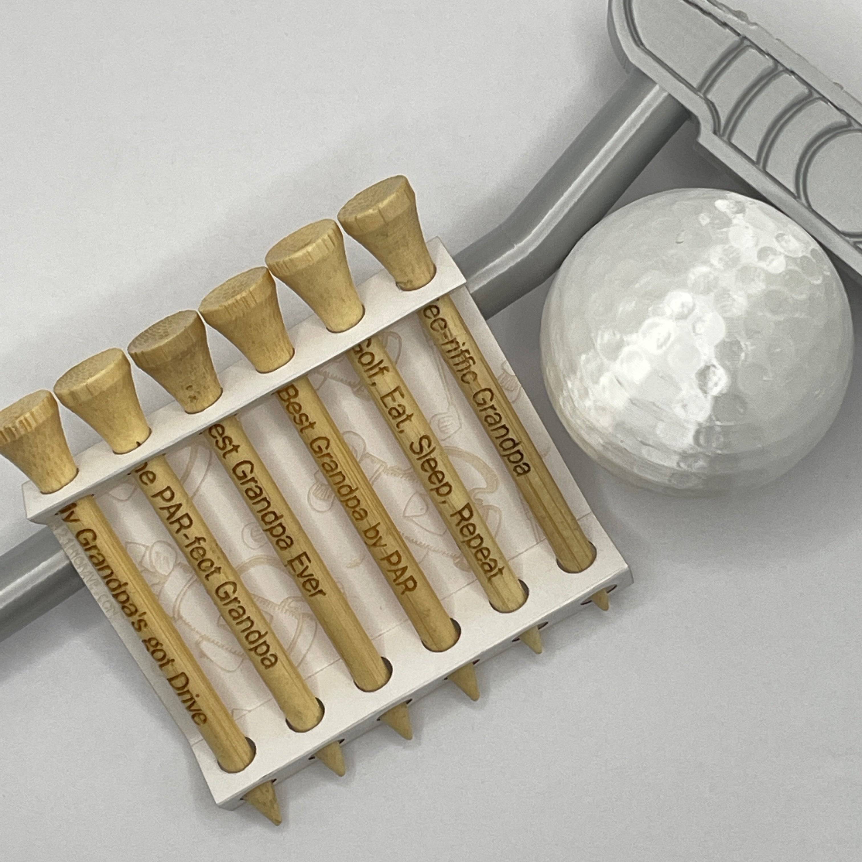 Close-up of engraved golf tees with ball and putter